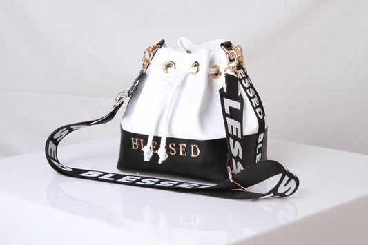 Repeatedly consuming the word Blessed is a form of Law of attraction according to the bible. Beautiful Black & White Color Block Bag with Gold tone hardware. Striking Attributes include the gold Blessed branding at the base of the bag and the huge Blessed nylon straps